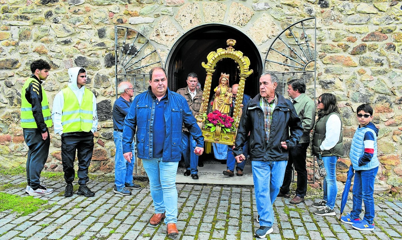 Simón Amuchastegui, a la izquierda, ayuda a sacar la imagen de la Virgen de la Luz de su ermita para la misa celebrada en la Venta de Piqueras.