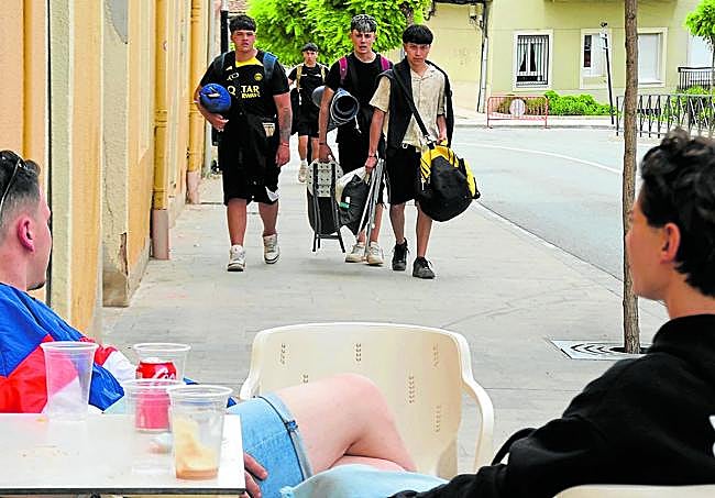 Varios 'holikers' suben por la calle Mediavilla con las bolsas y el equipaje que llevaron al camping.
