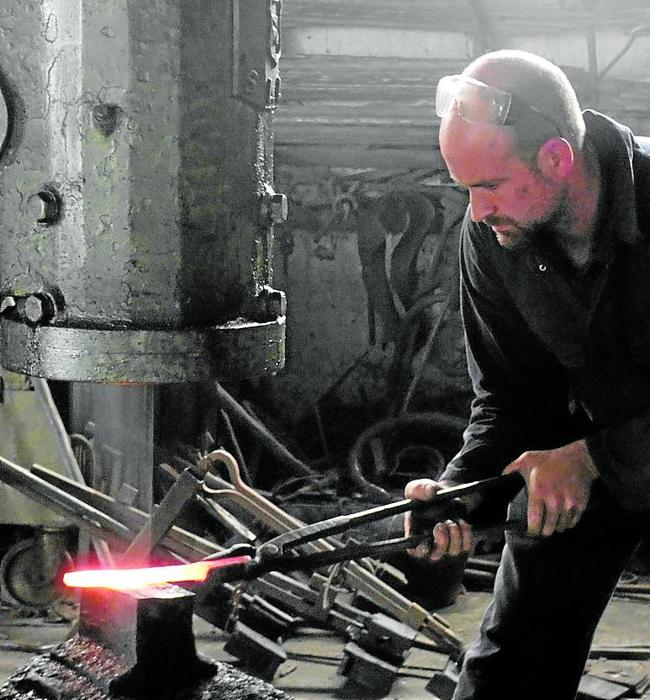 Daniel Tofé moldea una barra de hierro con el martillo pilón.