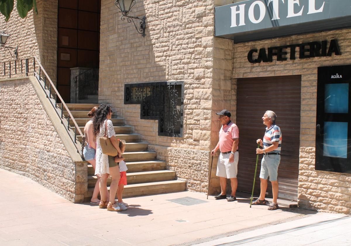 Varios vecinos de la localidad mantienen una conversación a las puertas del hotel, que lleva cerrado desde el pasado 8 de julio.