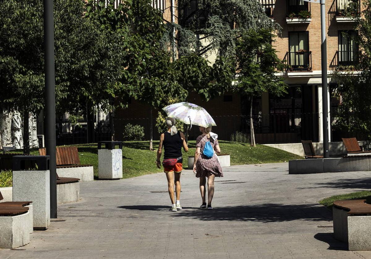 Dos mujeres se protegen del sol con un paraguas.