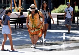 Varias personas se refrescan en una de las fuentes de la plaza Primero de Mayo.