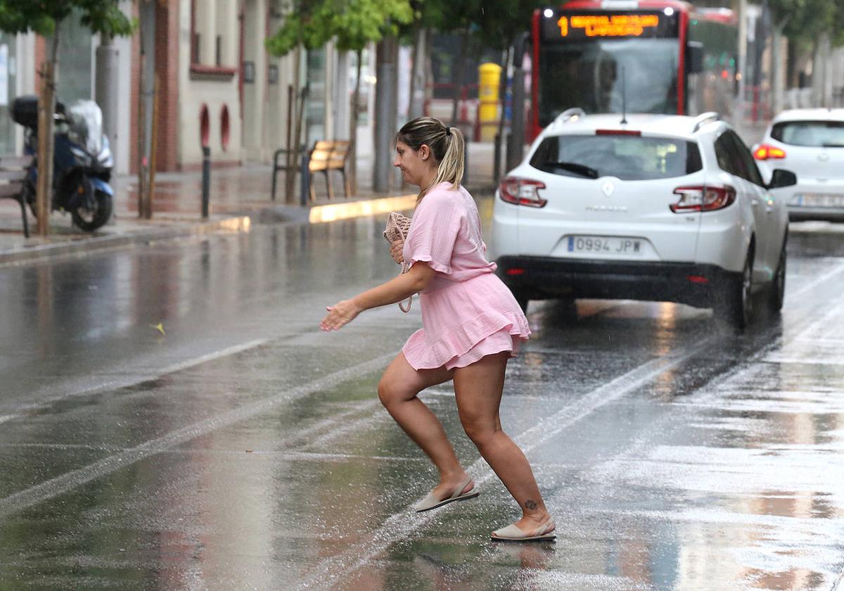 Una mujer busca cobijo bajo la lluvia que arrecia en Logroño.