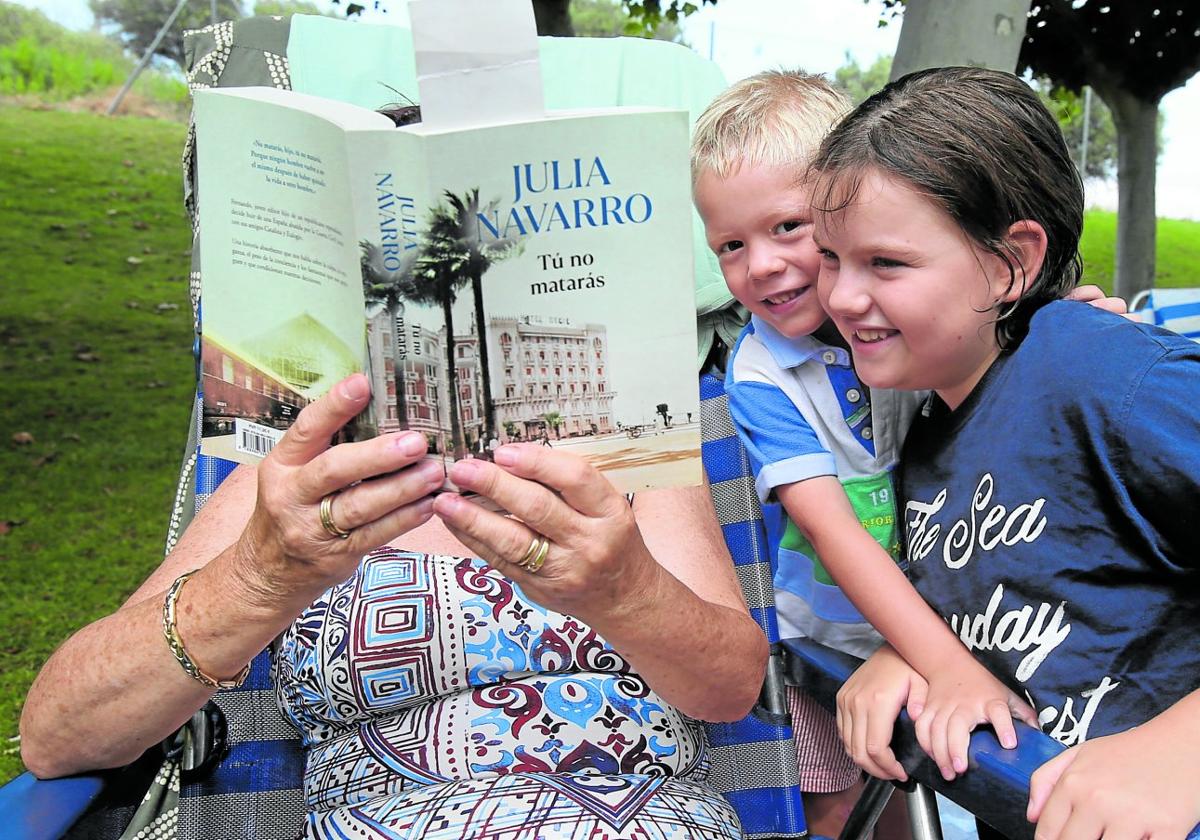 Mari Carmen, vecina de Navarra, junto a sus dos nietos, leyendo su libro 'Tú no matarás'.