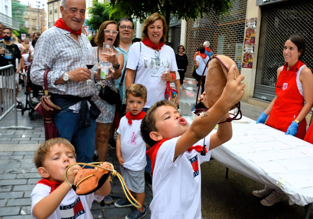 Mario y Marcos, bebiendo agua en bota, en la degustación de pan con tomate y jamón de la peña Philips.