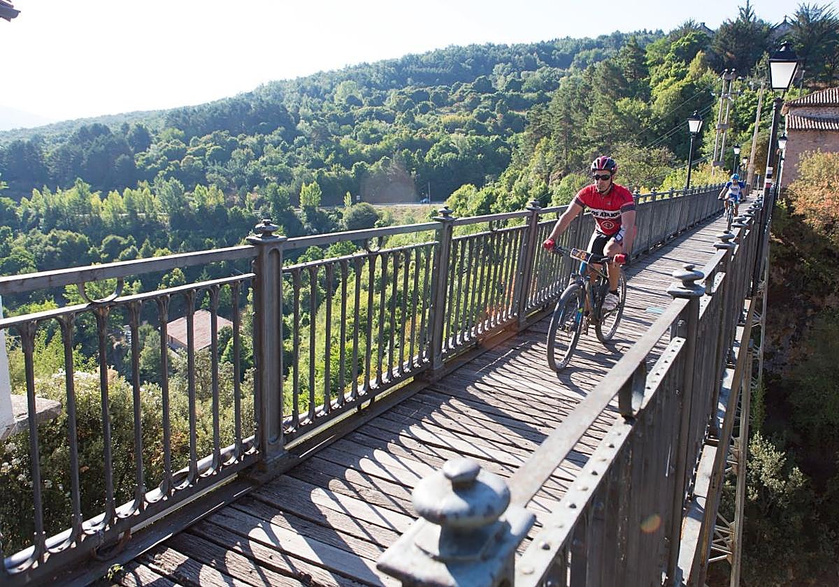 Unos ciclistas atraviesan el puente de hierro de Ortigosa de Cameros durante la prueba de BTT de Nieva de Cameros.