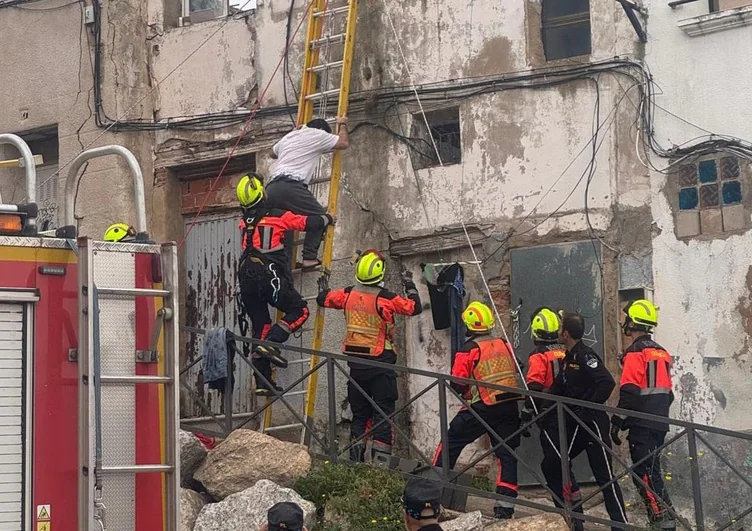 Los bomberos ayudan a salir al hombre con una escalera apoyada en la fachada.