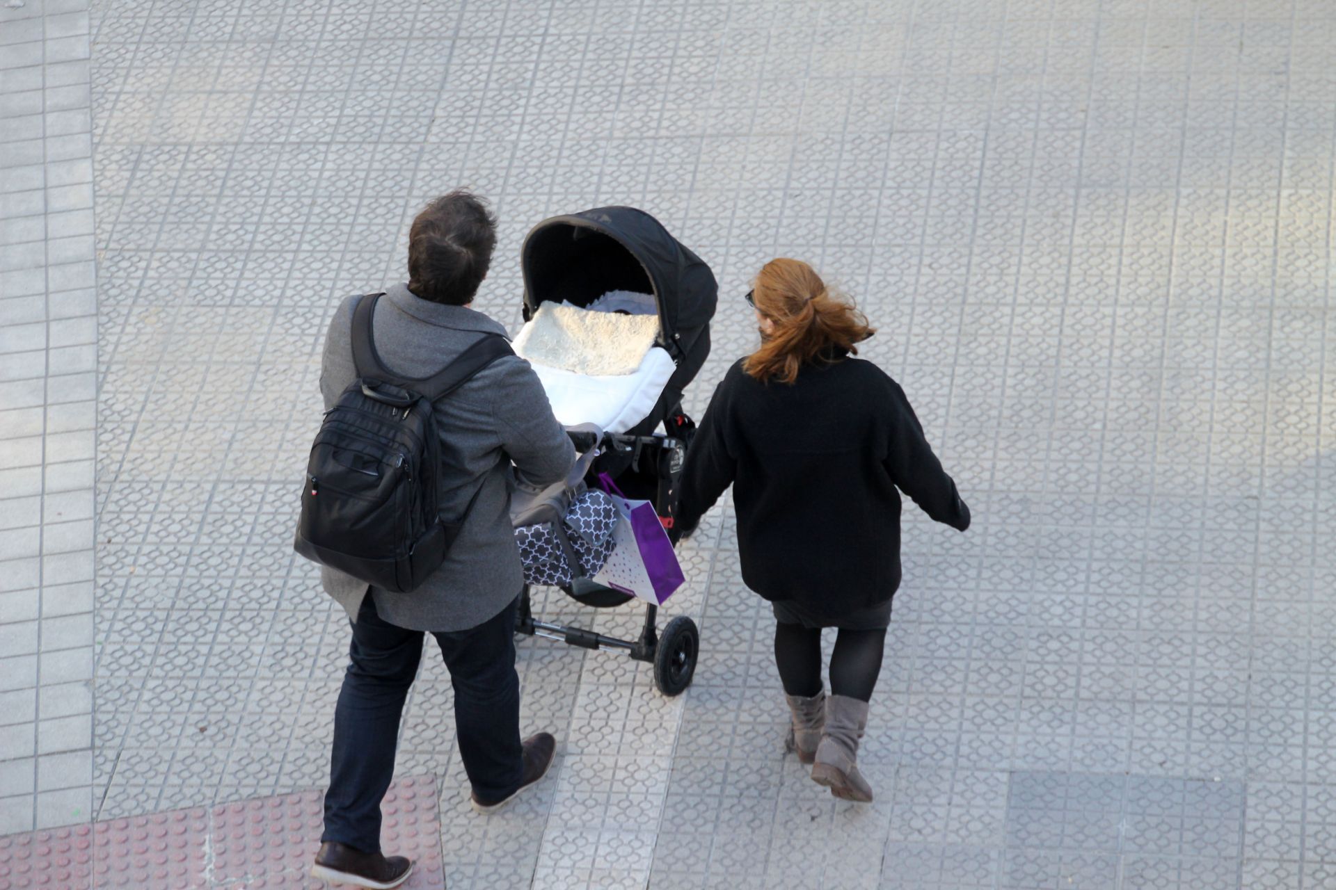 Dos padres pasean a su bebé en un carrito.