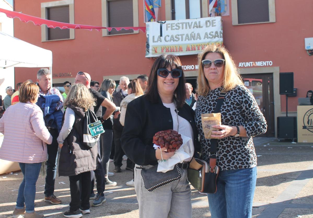 Dos amigas posan sonrientes, en la plaza, con sus castañas.