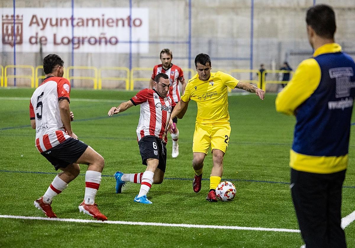 El local Vitorica conduce el balón ante dos jugadores del Autol.
