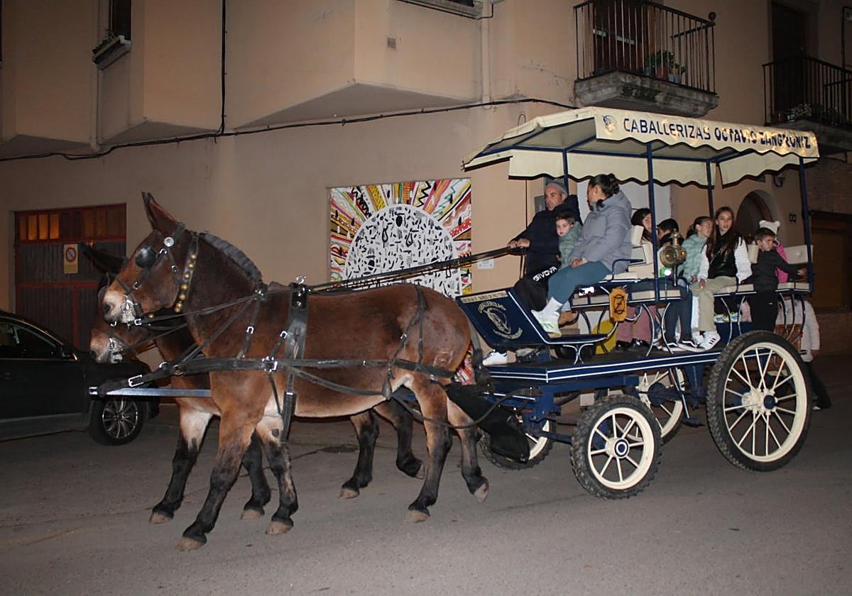 La calesa de 'Bañarte', cargada de niños, pasa por delante de una de las obras que decoran el pueblo.