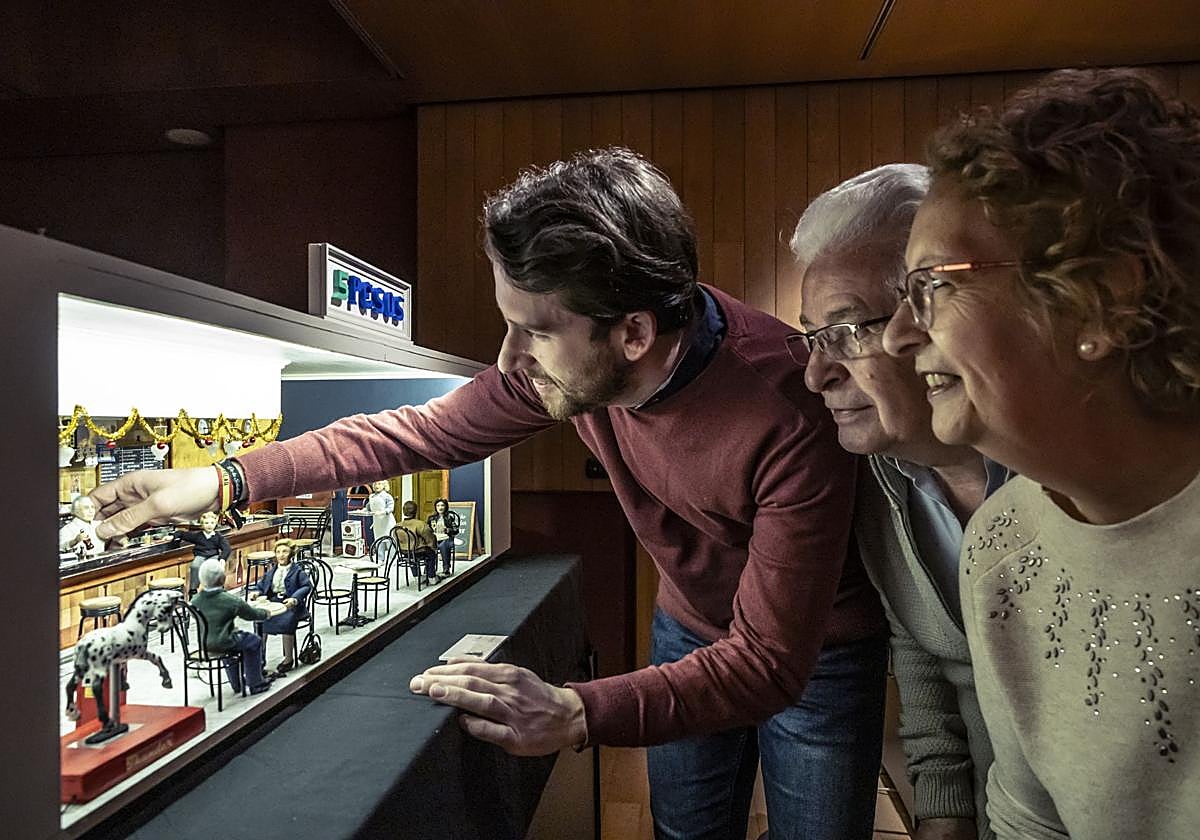 David, Martín y Mari Cruz, junto a la maqueta en miniatura del bar 5 Pesos, el regalo que el hijo les hizo a sus padres por su jubilación.