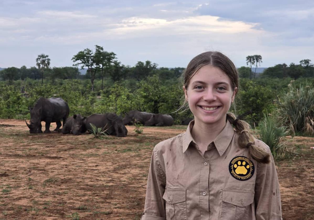 Elvia Gómez Troya posa sonriente junto a varios ejemplares de rinoceronte, en Zambia.