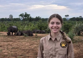 Elvia Gómez Troya posa sonriente junto a varios ejemplares de rinoceronte, en Zambia.