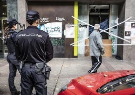 Un vecino pasa junto al lugar del crimen ante la mirada de dos agentes de la Policía Nacional