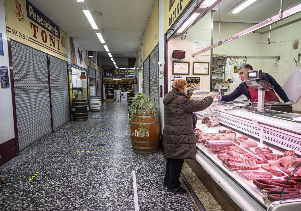 Rafael Adell atiende a una clienta en su carnicería del mercado Múgica.