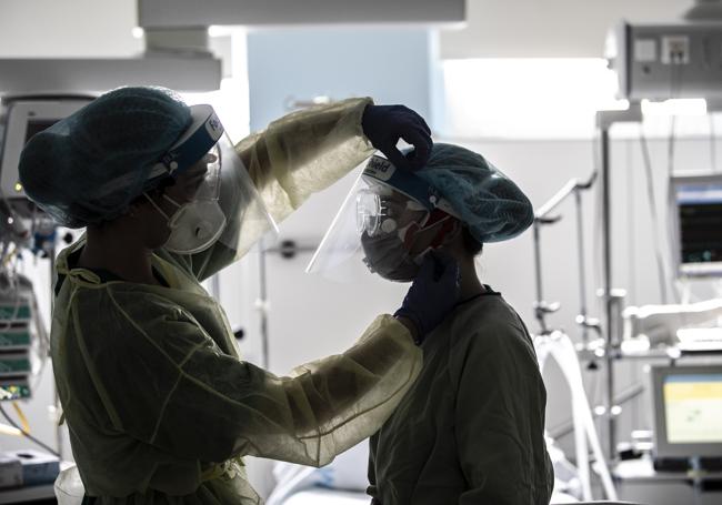 Dos profesionales sanitarias se colocan los equipos de protección para entrar a uno de los box de la UCI del Hospital San Pedro.