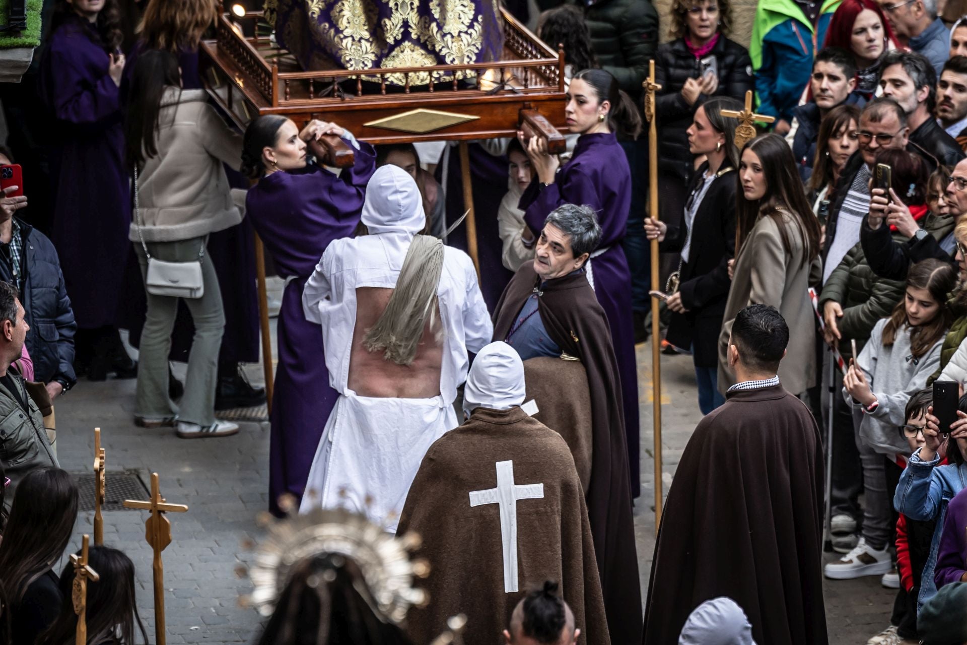 Mujeres que llevaban uno de lo pasos observan a uno de los Picaos mientras agita su madeja cumpliendo con su penitencia.