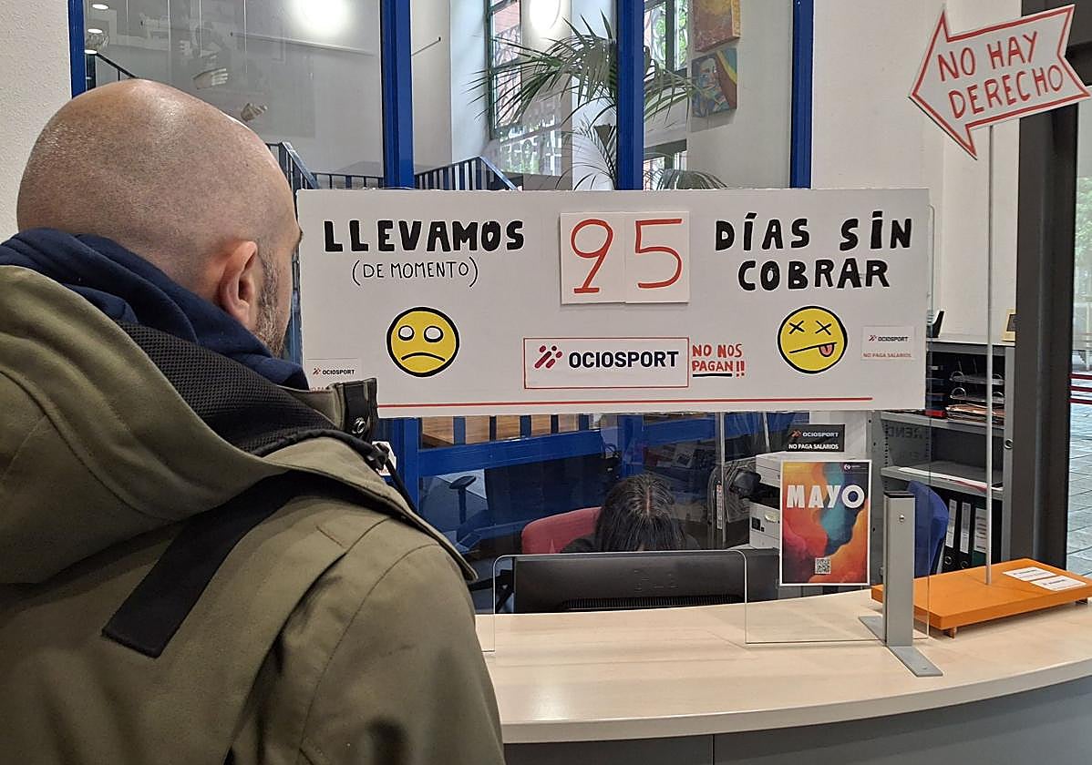 Un hombre observa el cartel de protesta por los impagos de los trabajadores de Ocio Sport en La Gota de Leche de Logroño.