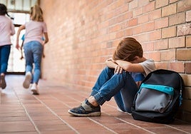 Un niño solo en un patio de una escuela.