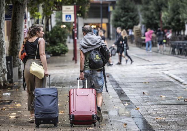 Dos turistas caminan por Logroño con sus maletas.