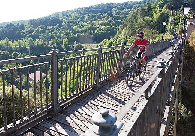 Un ciclista circula por el puente de hierro de Ortigosa.