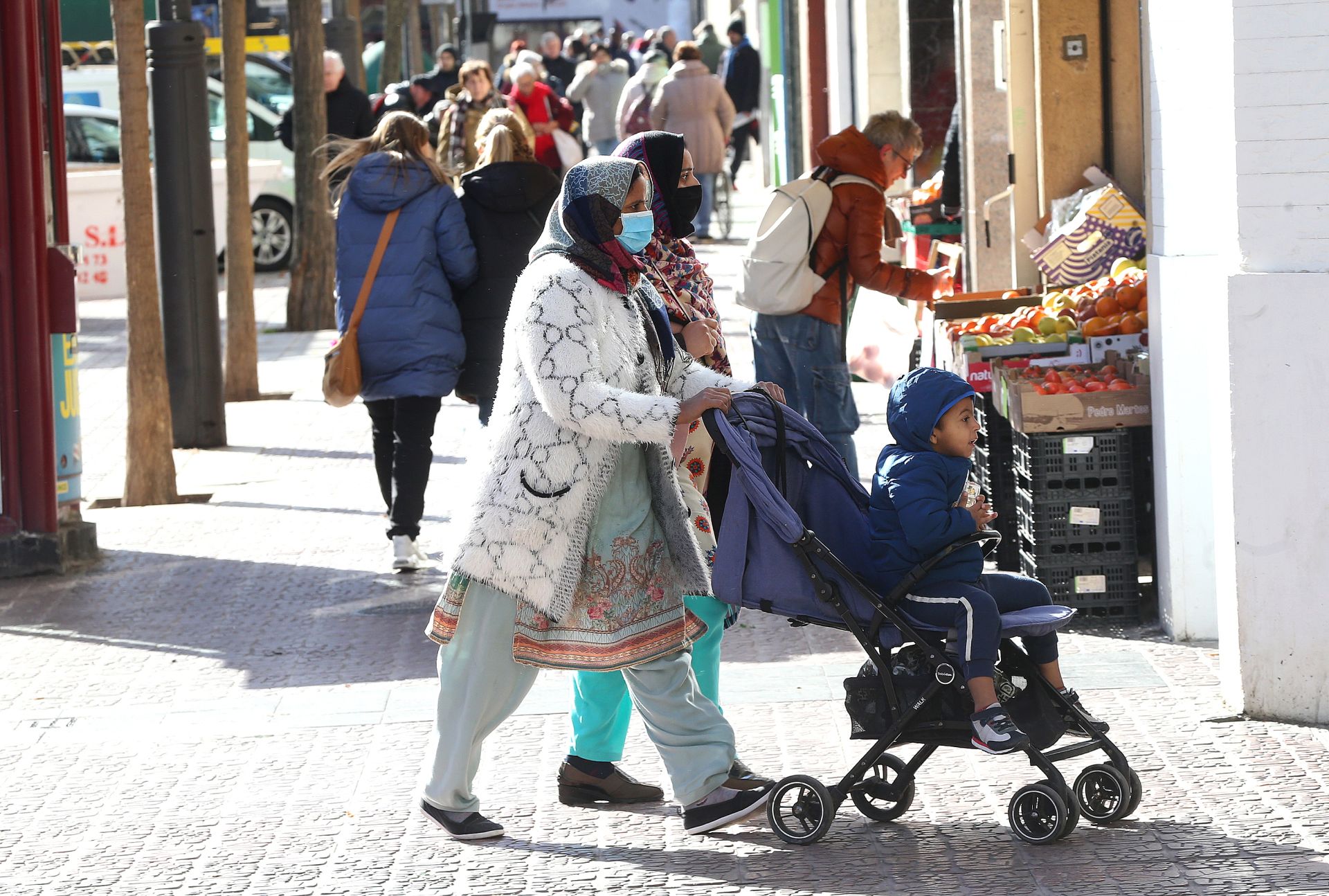 Dos mujeres extranjeras pasean un carrito en una concurrida calle de Logroño.