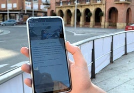 Aplicación de Bizum en un teléfono móvil y el Ayuntamiento de Calahorra al fondo.