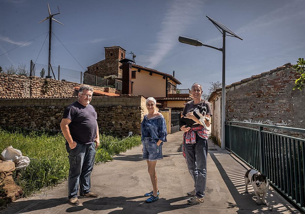 Luis Argaiz, Isabel y Bruno posan en Carbonera, ante las farolas de energía fotovoltaica y el aerogenerador doméstico de un vecino.