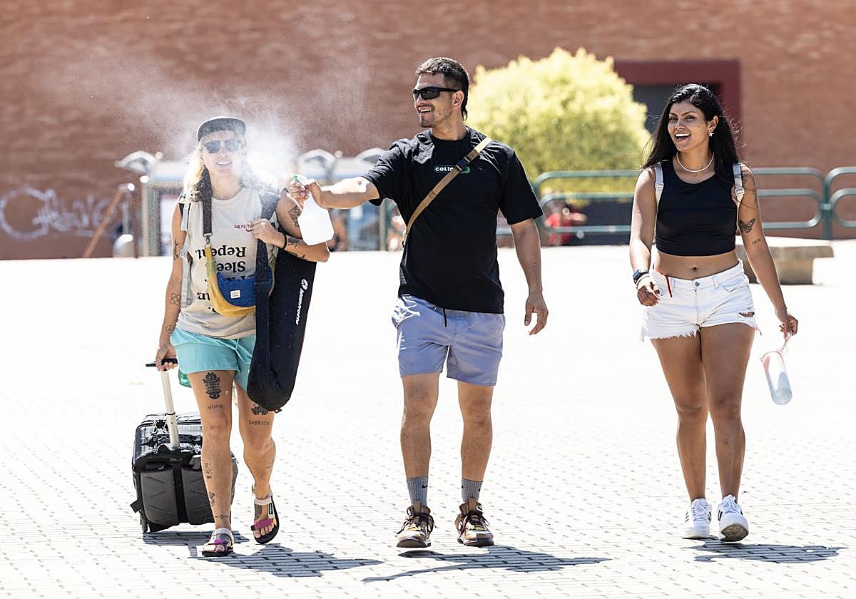 Unos jóvenes se refrescan con agua en el entorno de Las Norias.