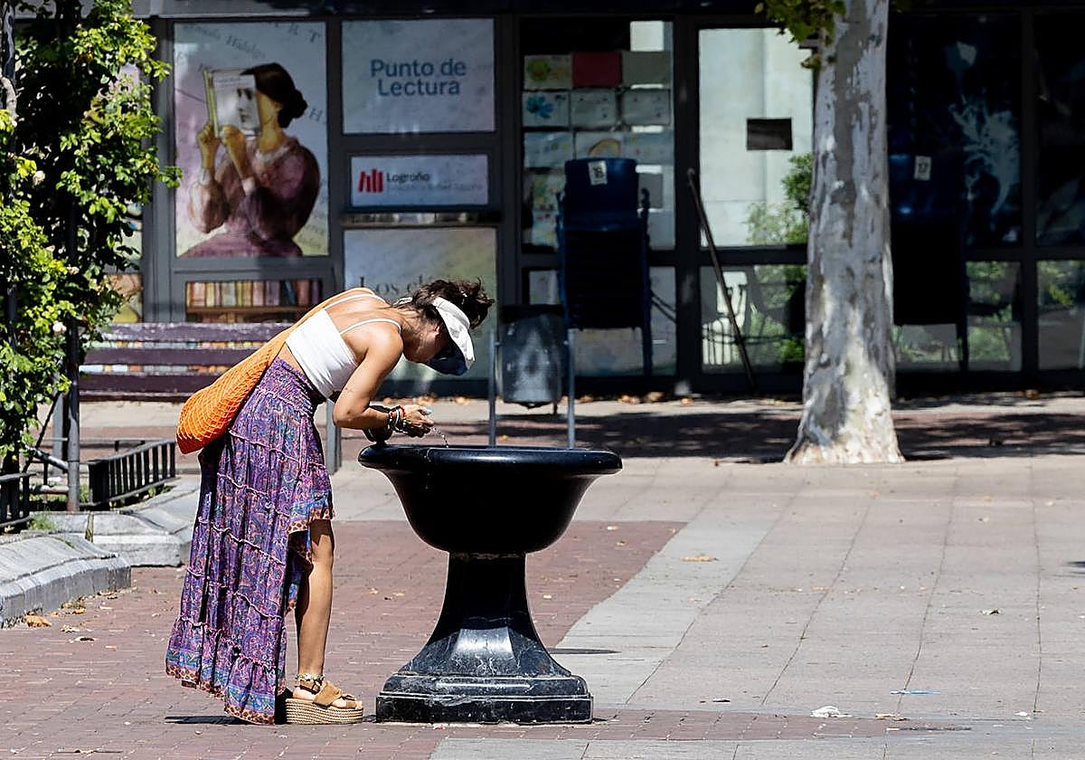 Una mujjer se refresca en la fuente pública del Espolón.