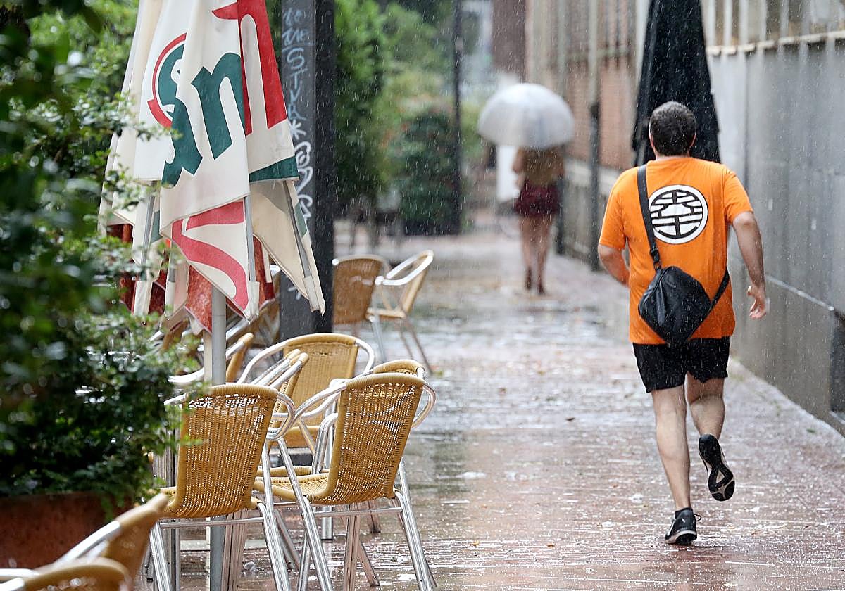 Un hombre corre para refugiarse de la lluvia en Logroño.