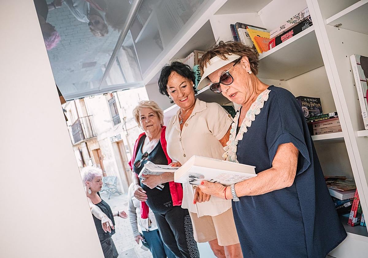 Varias mujeres ojeaban libros en la biblioteca móvil durante su visita a San Vicente.