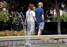 Dos personas pasean por El Espolón logroñés bajo el sol.