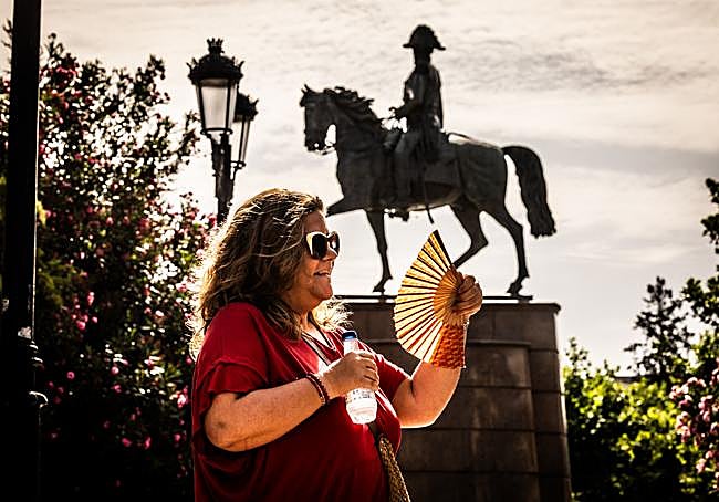 Una mujer, con una botella de agua y un abanico, en el Espolón logroñés, en uno de los días de la primera ola de calor de este verano.