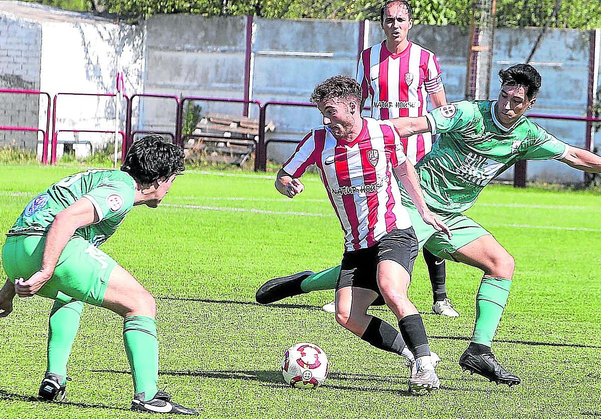 Carlos Benítez maniobra entre dos jugadores del Náxara.