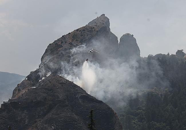 Los bomberos intentan controlar el incendio en las Peñas de Viguera con el uno de los helicópteros.