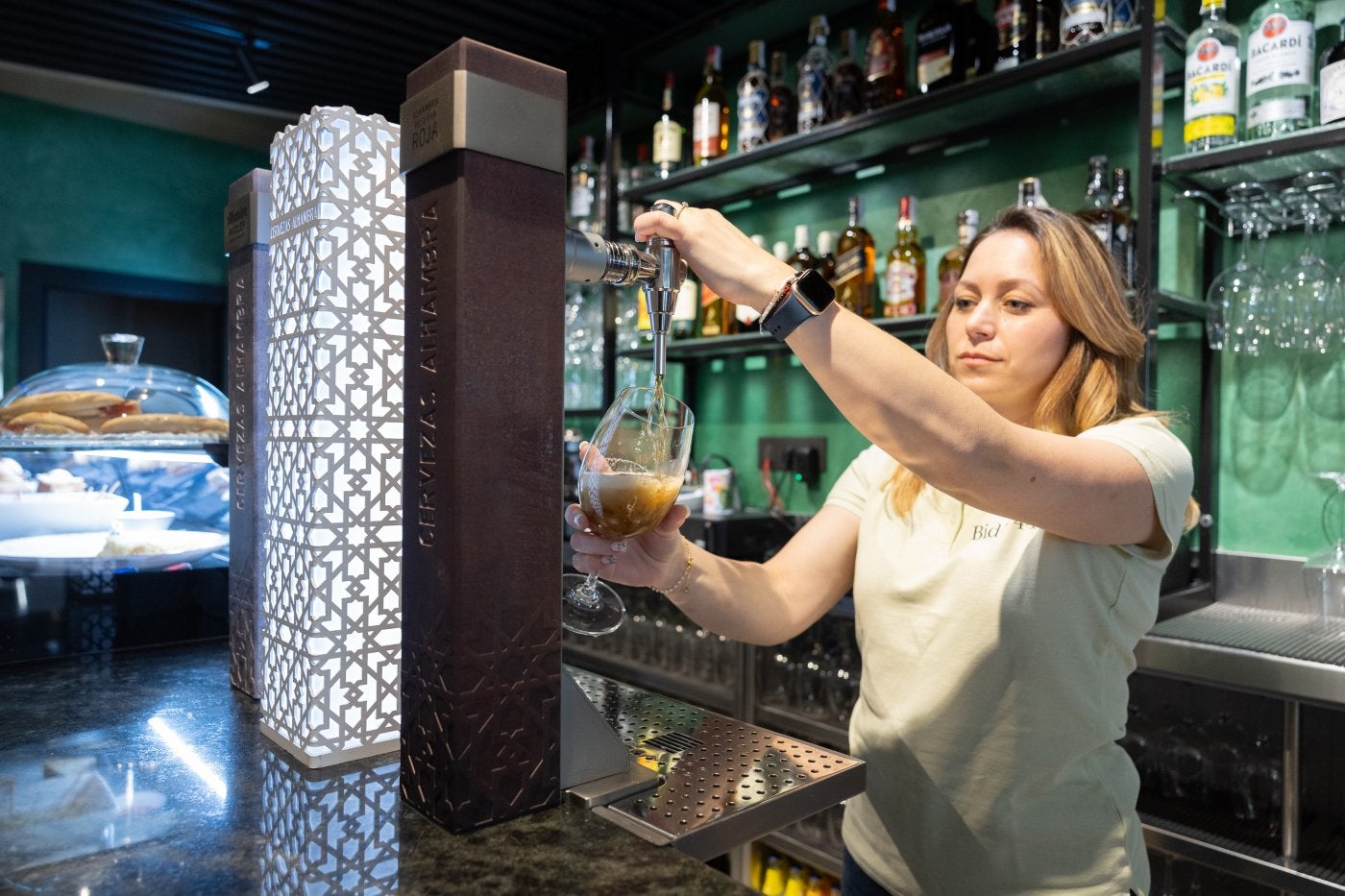 Una camarera sirve una caña.
