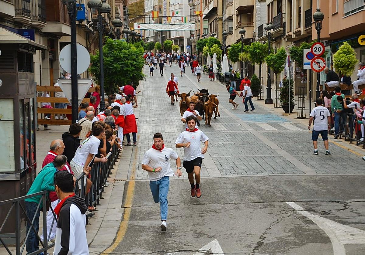Varios aficionados corren delante de las vacas por la calle Mártires.