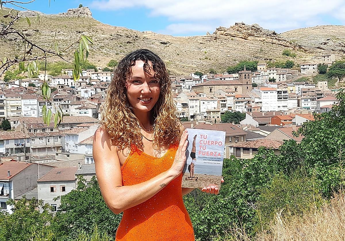 Clara Martínez-Polo Diana con su libro 'Tu cuerpo, tu fuerza. Calistenia y hábitos para una vida saludable' y al fondo Cervera.