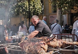 Un hombre corta una ternera ecológica asada en la plaza de la Diversidad.
