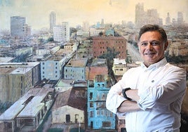 El artista Manuel Romero posa ante su pintura de La Habana.