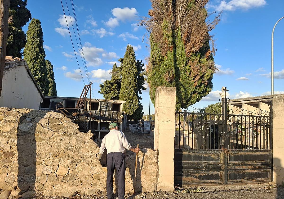 Un hombre observa los desperfectos ocasionados en el muro de entrada al cementerio.