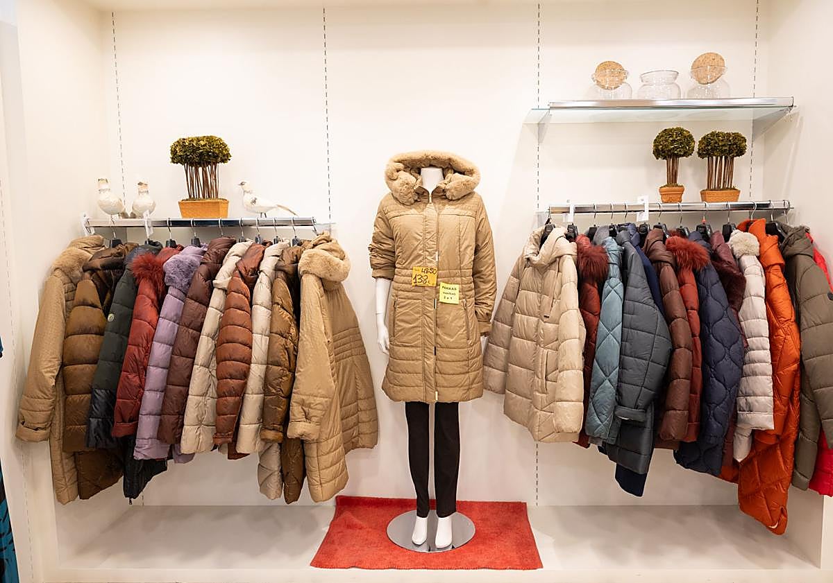 Imagen principal - Dos detalles del stock de la tienda y Natalia colocando un collar en el escaparate.