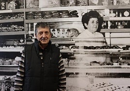 Jesús Manuel Cacho junto a un mural de la pastelería en el que aparece su madre, María Cruz.