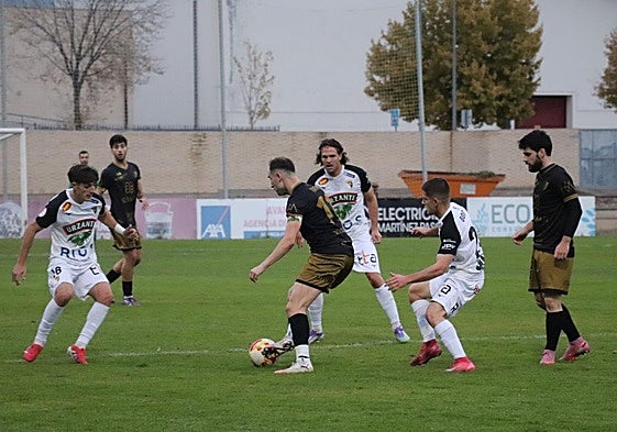 El alfareño Arturo Fernández, uno de los goleadores del pasado domingo, toca entre la defensa del Tudelano y el apoyo de varios compañeros.