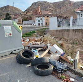 Neumáticos y otros residuos junto a un contenedor de Quel.