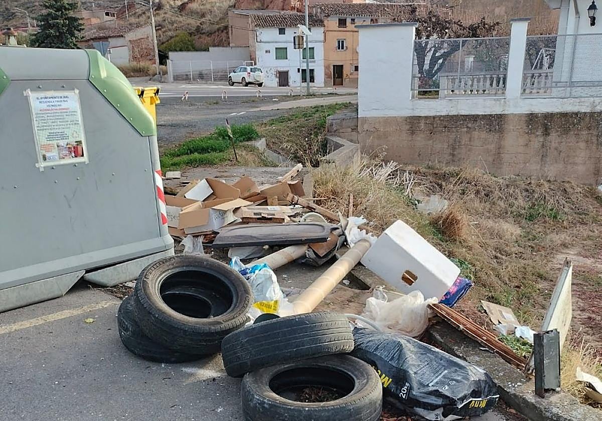 Neumáticos y otros residuos junto a un contenedor de Quel.