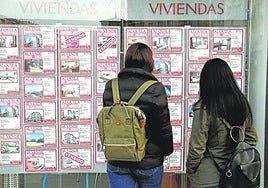 Dos mujeres miran los precios de los pisos en un escaparate.