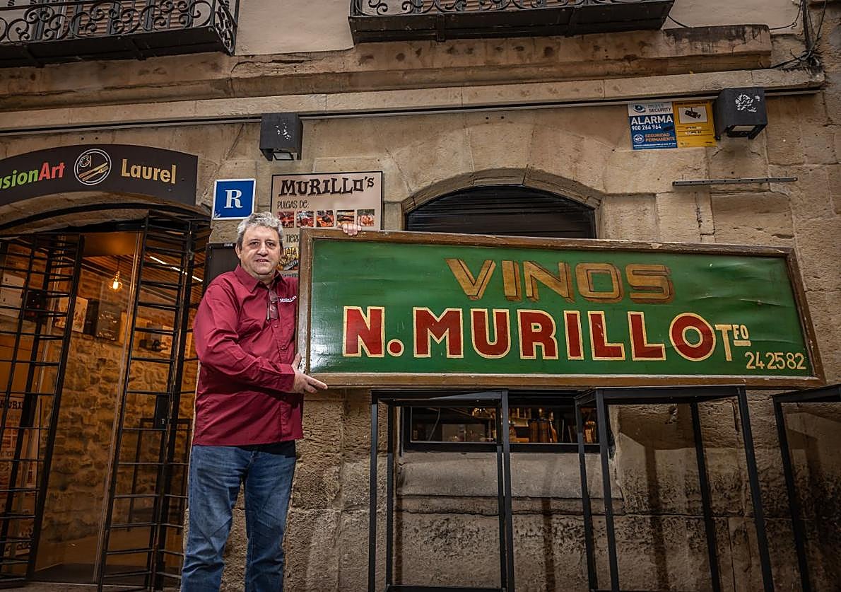 José María Murillo, en la puerta de su local, con un viejo cartel de un antiguo negocio familiar.